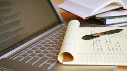 A yellow notepad on top of a laptop